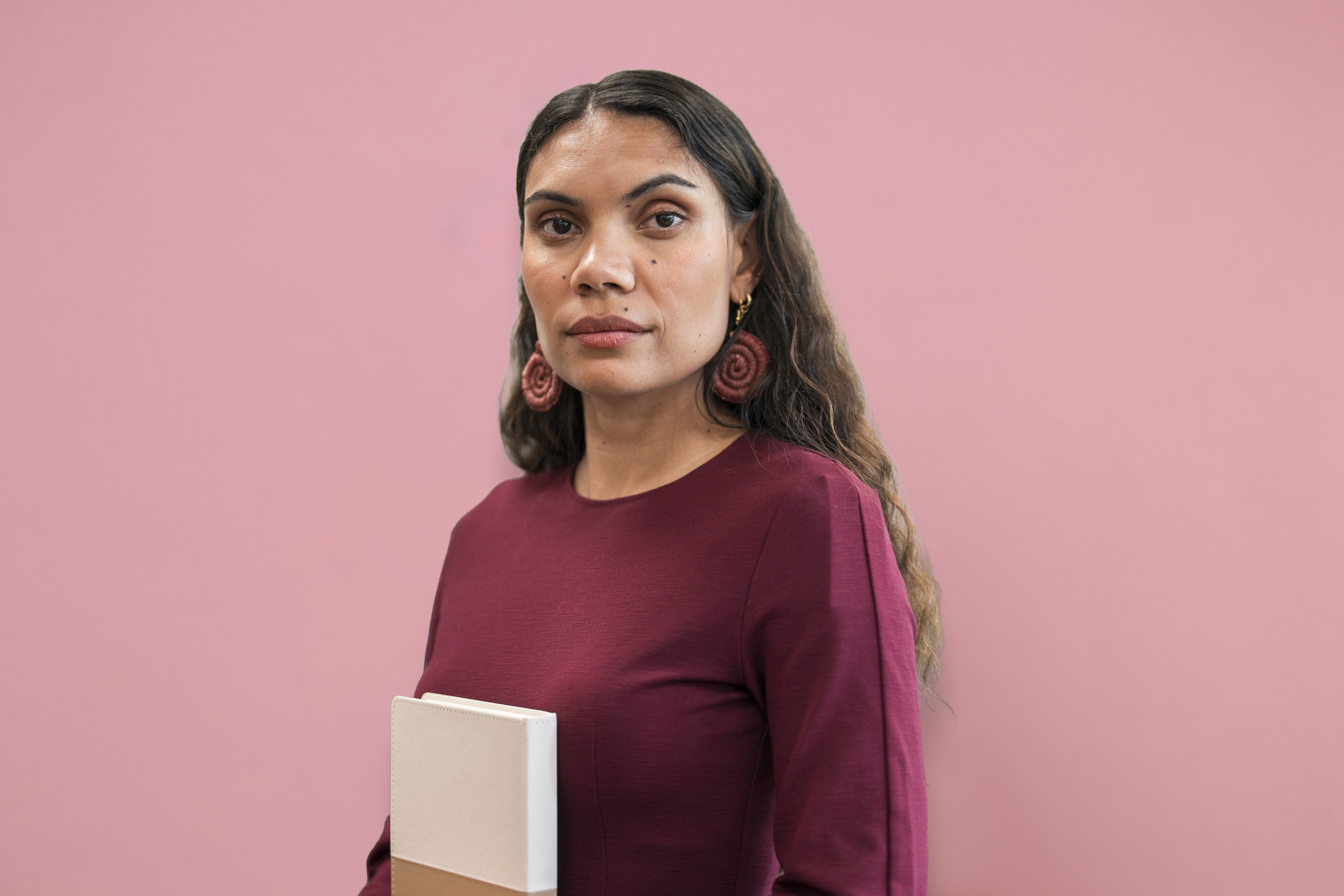 Image of a person standing side on looking to camera on pink background